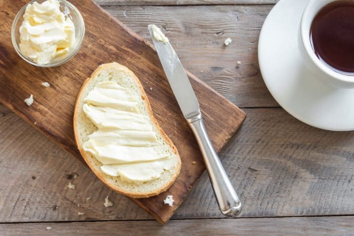 vegan butter spread into a slice of bread sitting beside a bread knife