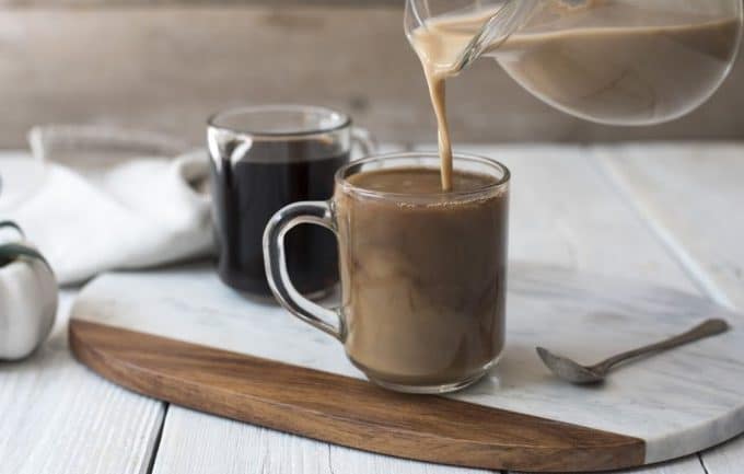 a vegan coffee creamer pouring over a mug of black coffee